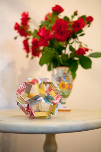 une table avec un vase avec des fleurs rouges et une boîte dans l'établissement La Maison De Siloe, à Villefranche-de-Rouergue