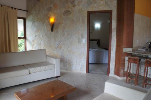 a living room with a white couch and a stone wall at Pousada Morada dos Ventos in Pipa