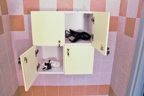 a white cabinet with two black shoes in it at Ostello La Miniera in Massa Marittima