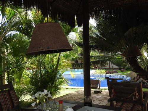 a table with a lamp in front of a pool at Pousada Morada dos Ventos in Pipa