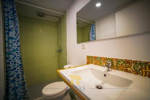 a bathroom with a sink and a toilet and a mirror at Antas Guest House in Esposende