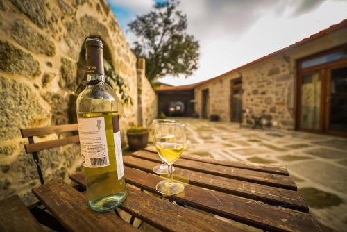 a bottle of wine and a glass sitting on a wooden bench at Antas Guest House in Esposende