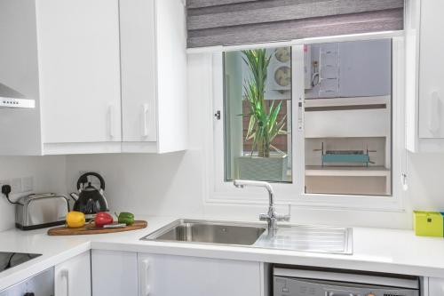 a white kitchen with a sink and a window at Marimar villa in Protaras