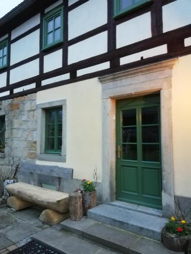 a building with a green door and a bench at Lichtenhainer Hof in Lichtenhain