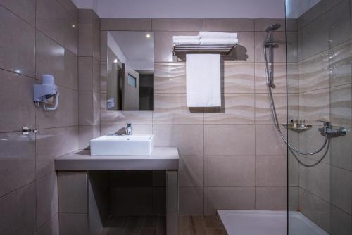 La salle de bains est pourvue d'un lavabo et d'une douche. dans l'établissement Thania Seaside Smotel - Adults Only, à Agia Pelagia