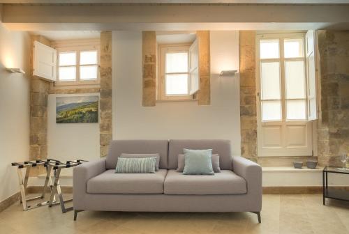a living room with a couch and two windows at Palazzo Alfeo Aparthotel in Siracusa