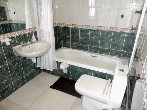 a green tiled bathroom with a toilet and a sink at Mountain Mist in Bettyʼs Bay