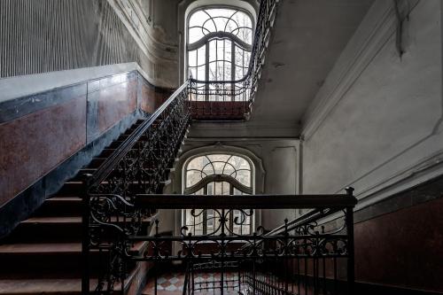 a staircase in an old building with two windows at Leosphere Hostel in Lviv