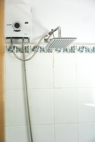 a shower head in a bathroom with white tiles at YAMA APARTMENTS - Private Beachfront in General Luna