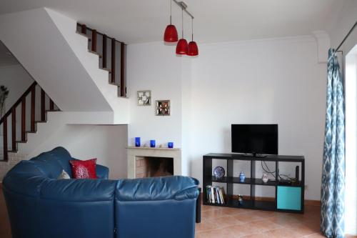 a living room with a blue couch and a staircase at Cantinho da Cacilda in Grândola