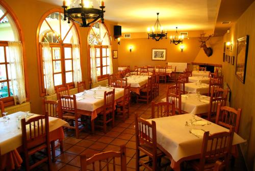 a restaurant with white tables and chairs and windows at La Noguera in Palomera