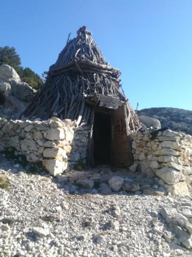 a small stone building with a thatched roof at Casa M&M in Cala Gonone