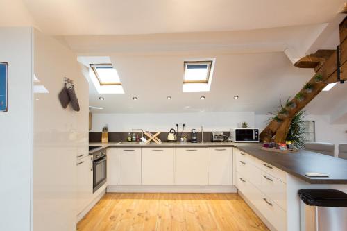 - une cuisine mansardée avec des armoires blanches et des lucarnes dans l'établissement LB Vacation Rentals I Big Loft 107m2, 10min Walk to Palais des Festivals, à Cannes