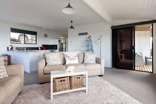 a living room with a couch and a table at KINGFISHER COTTAGE Beachfront at the Binalong Bay in Binalong Bay