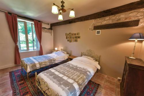 a bedroom with two beds and a window at Le Prieuré La Ferme in Souillac