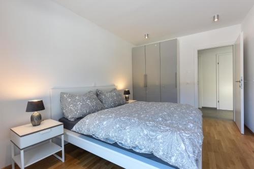 a white bedroom with a bed and a nightstand at Seechalet in Altossiach