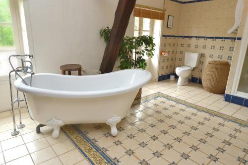 a bathroom with a white tub and a toilet at Le Prieuré La Ferme in Souillac
