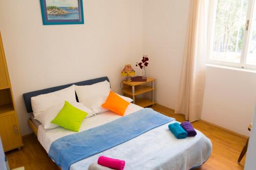 sypialnia z łóżkiem z kolorowymi poduszkami w obiekcie Tania Apartment w mieście Prižba