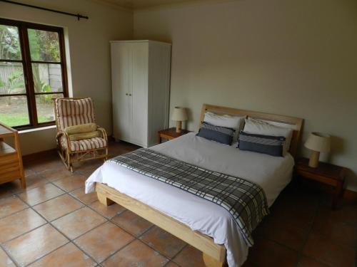 a bedroom with a large bed and a chair at Sunset at Diluta in Cape Town