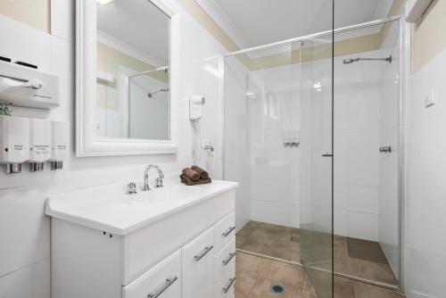 a white bathroom with a sink and a shower at Garden City Motor Inn in Wagga Wagga