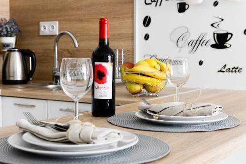 M&R Apartament Airport&Business Premium Komputerowa - underground garage - free WiFi - Netflix - self check-in - 5 min from Chopin Airport في وارسو: زجاجة من النبيذ موضوعة على طاولة مع كأسين