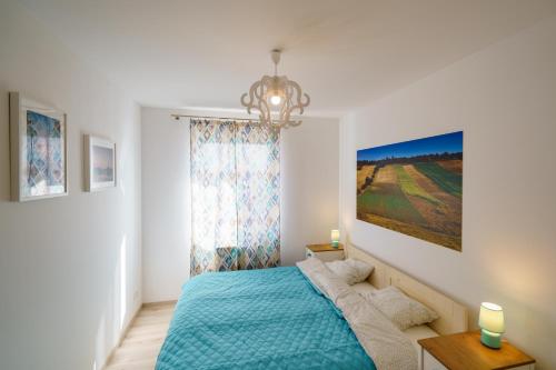a bedroom with a blue bed and a chandelier at Apartament z tarasem in Kielce