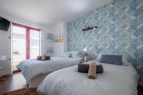 two beds in a room with blue wallpaper at B&B do Paço in Lagos
