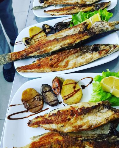 two plates of fish and potatoes on a table at ROOMS balani in Shkodër