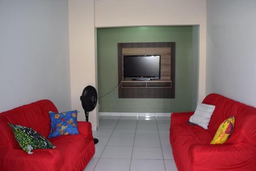 a living room with two red couches and a flat screen tv at CASA para até 10 PESSOAS in Boa Vista