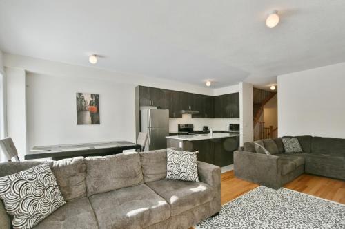 a living room with a couch and a kitchen at New Blue Mountain Village Snowbridge Executive Townhome Sleeps 10 with Outdoor Pool and Shuttle in Nottawa