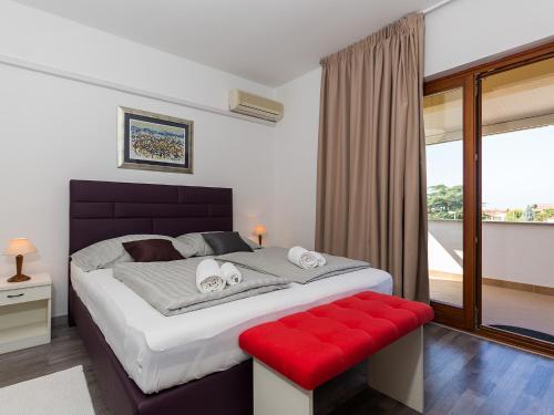 1 dormitorio con 1 cama grande y banco rojo en Ulika Rooms & Apartments, en Poreč