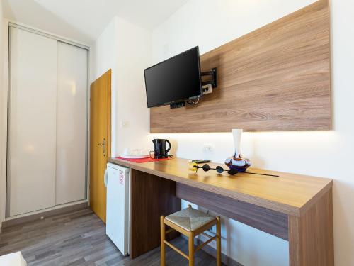 Habitación con escritorio y TV en la pared. en Ulika Rooms & Apartments, en Poreč