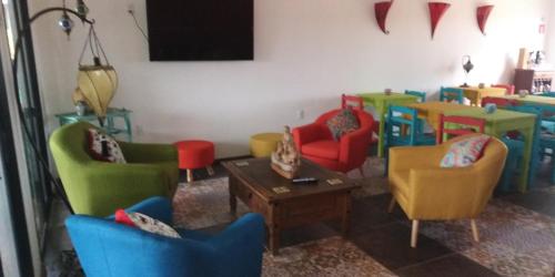 uma sala de estar com cadeiras coloridas e uma mesa em El Bodegón Hostal Boutique em Punta Del Diablo