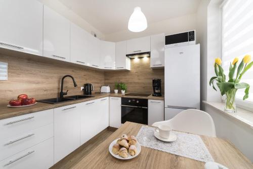 a kitchen with white cabinets and a table with a bowl of food at Apartament Sweet House in Olsztyn