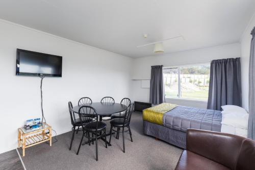 a bedroom with a bed and a table and chairs at Foxton Beach Holiday Park in Foxton Beach