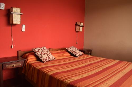 um quarto vermelho com uma cama com duas almofadas em Terrazas Del Lago em Cabra Corral