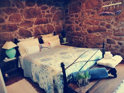 - une chambre avec un lit et un mur en pierre dans l'établissement Casa da Azenha II, à Sabugal