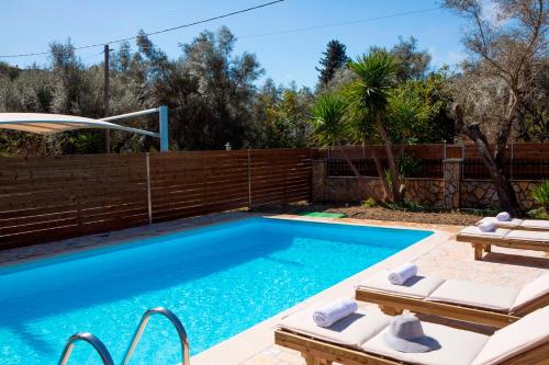 a swimming pool with two loungers next to a fence at Red Villa in Nydri