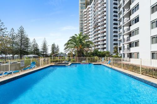 una gran piscina con sillas y un edificio en Sandpiper Broadbeach en Gold Coast