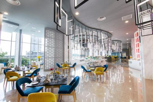 a dining room with tables and chairs and chandeliers at Fraser Place Puteri Harbour in Nusajaya