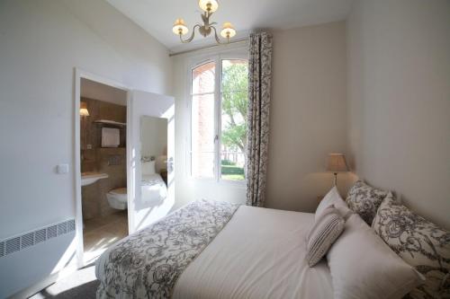 a bedroom with a bed and a window and a bathroom at La Maison d'Emilie in Houlgate