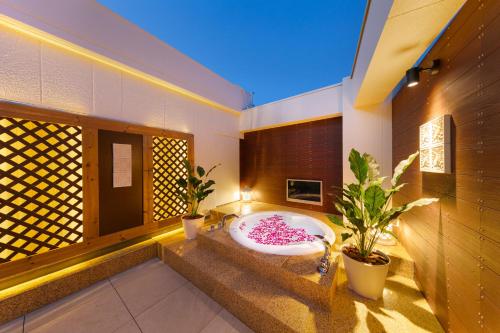 Hotel Eldia Modern Kobe(Adult Only) في كوبه: حمام مع حوض استحمام مع اثنين من النباتات الفخارية