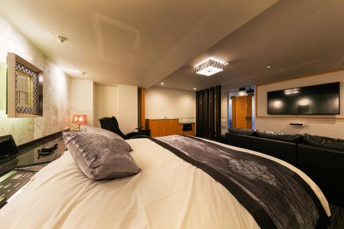 a bedroom with a large bed with a tv on the wall at Hotel Eldia Modern Kobe(Adult Only) in Kobe