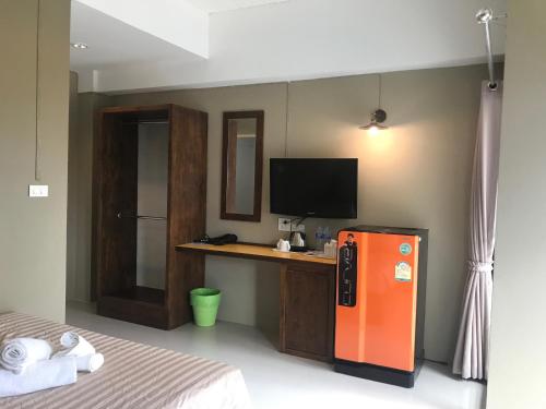 1 dormitorio con nevera de color naranja y escritorio en Baan Ton Chan, en Chao Lao Beach
