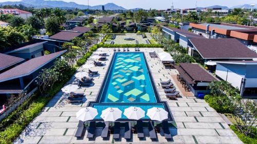 an overhead view of a swimming pool with umbrellas and chairs at Coral Tree Villa Huahin in Cha Am
