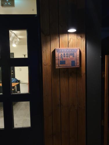 a sign on a wooden wall next to a door at Sokcho Hutte in Sokcho