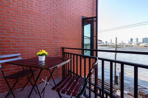 a table and chairs on a balcony with a brick wall at Lilliput Riverside Bangkachao in Samutprakarn
