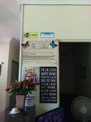 a wall with a sign on it with a plant at Hotel Morning Glory in Kudat