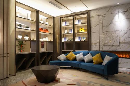 a living room with a blue couch and a fireplace at Auto City Ruili Hotel in Jiading
