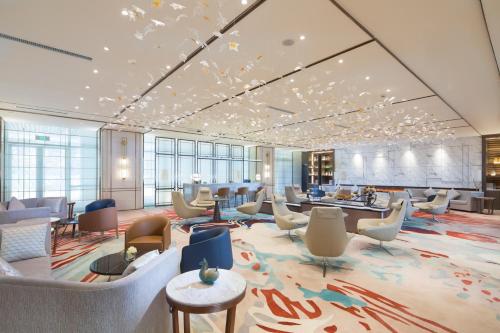 a lobby with a waiting room with chairs and tables at Auto City Ruili Hotel in Jiading